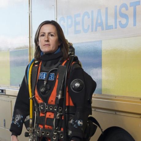 Lorna Dennison-Wilkins, in scuba gear in front of a police vehicle.