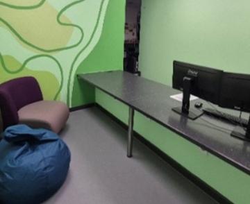 A close up of a custody suite, with green painted walls, bean bags and desktop computers.